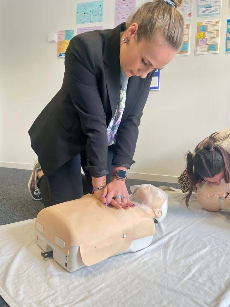 Une professionnelle qui réalise un exercice de formation pratique de massage cardiaque sur un mannequin adulte.